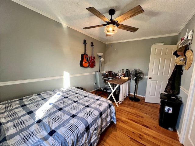 bedroom with a textured ceiling, ornamental molding, wood-type flooring, and ceiling fan