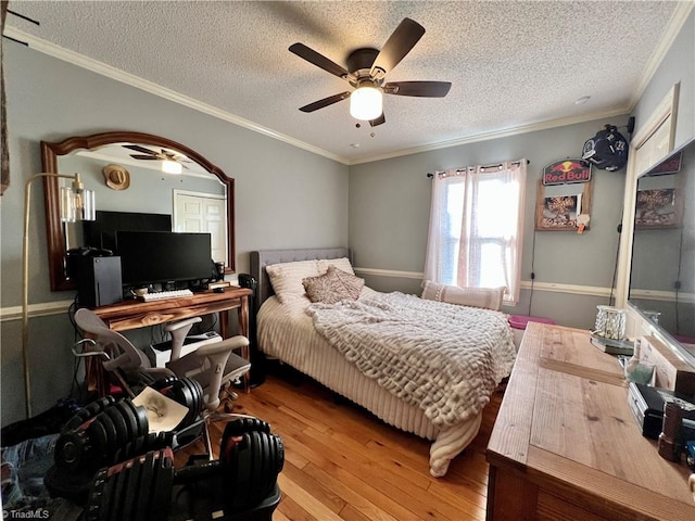 bedroom featuring crown molding, hardwood / wood-style flooring, ceiling fan, and a textured ceiling