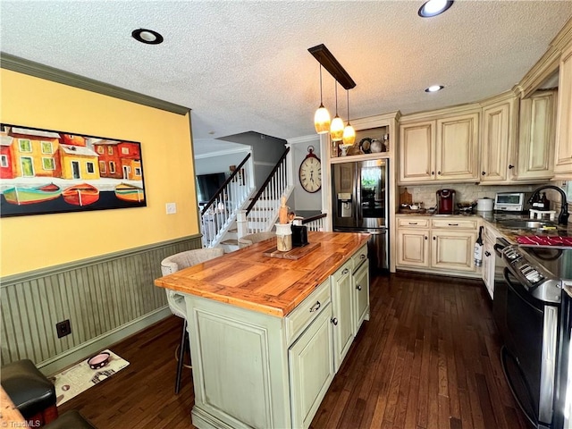 kitchen with stainless steel refrigerator with ice dispenser, stove, butcher block counters, crown molding, and pendant lighting