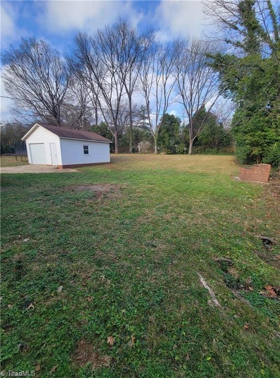 view of yard with a garage and an outbuilding