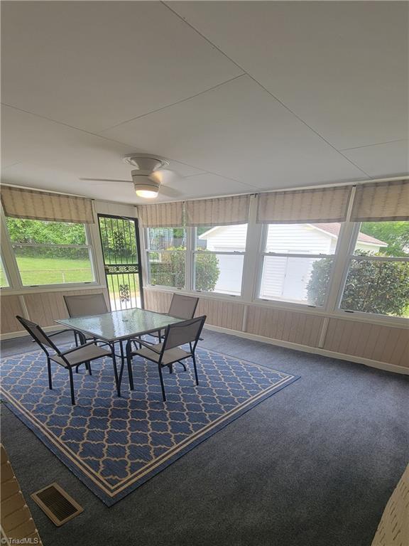 sunroom / solarium with a ceiling fan, visible vents, plenty of natural light, and outdoor dining space