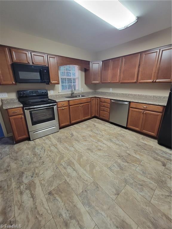 kitchen featuring brown cabinets, appliances with stainless steel finishes, light countertops, and a sink