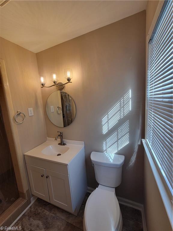 bathroom featuring a stall shower, baseboards, vanity, and toilet