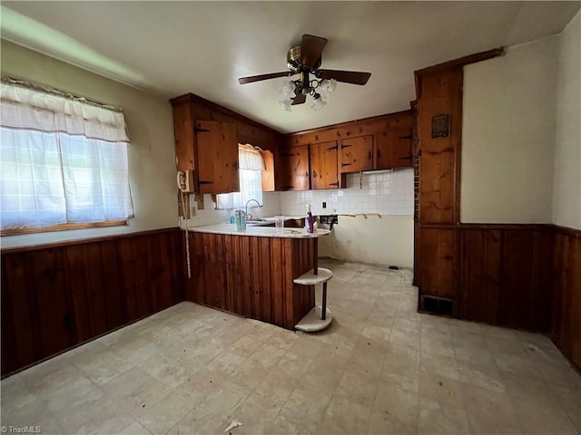 kitchen featuring sink, decorative backsplash, ceiling fan, kitchen peninsula, and a breakfast bar area