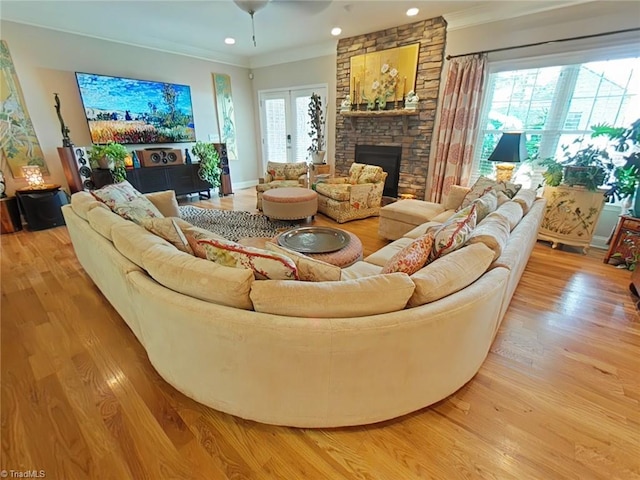 living room with a healthy amount of sunlight, ornamental molding, a fireplace, and light hardwood / wood-style flooring