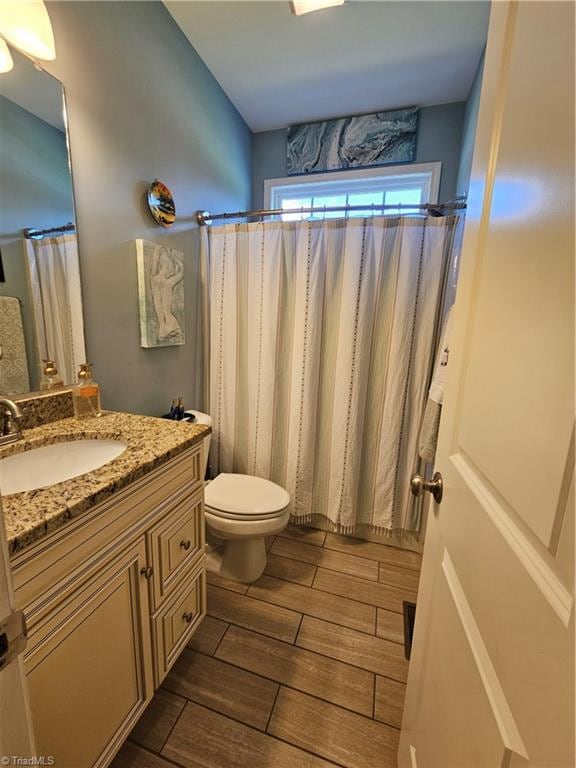 bathroom featuring hardwood / wood-style floors, vanity, toilet, and a shower with shower curtain