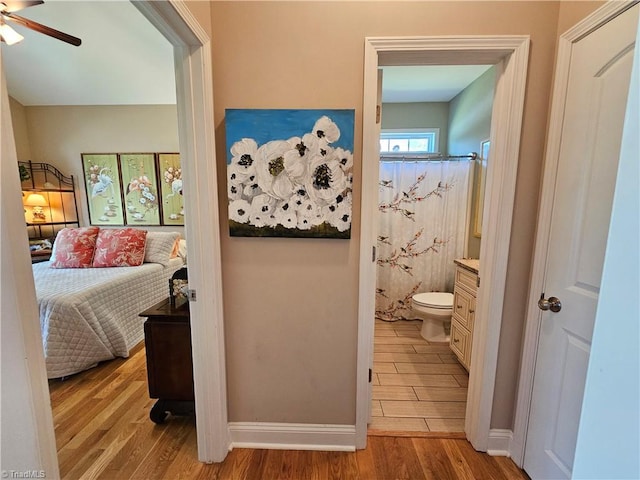 bedroom featuring light wood-type flooring, ensuite bathroom, and ceiling fan