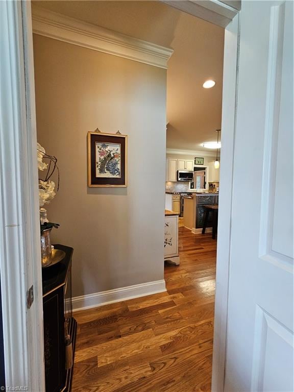 hallway with wood-type flooring and ornamental molding