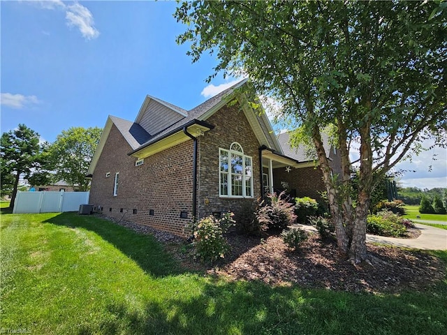 view of side of home featuring a yard and central AC