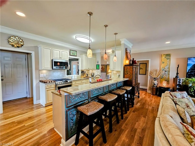 kitchen featuring a kitchen bar, light hardwood / wood-style flooring, pendant lighting, and appliances with stainless steel finishes