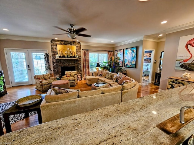 living room featuring crown molding, ceiling fan, a healthy amount of sunlight, and light wood-type flooring