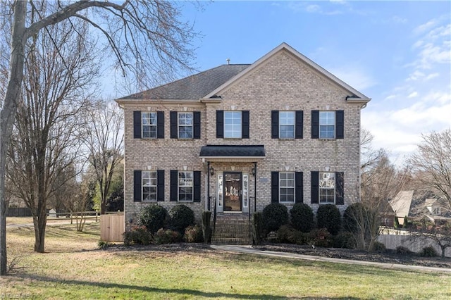 view of front of property featuring brick siding, a front yard, and fence