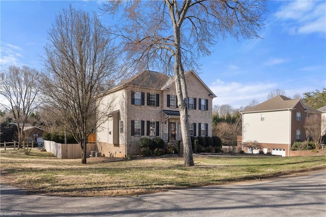 view of front of property featuring brick siding, a front lawn, and fence