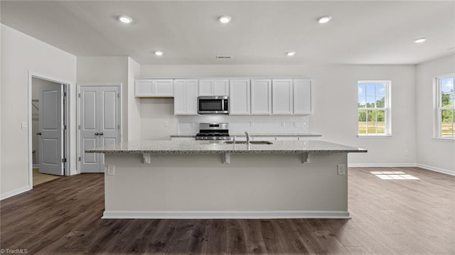 kitchen with white cabinets, stainless steel appliances, and an island with sink