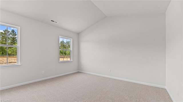 carpeted spare room with vaulted ceiling