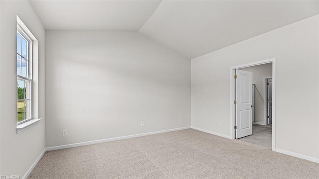 empty room with light carpet and vaulted ceiling