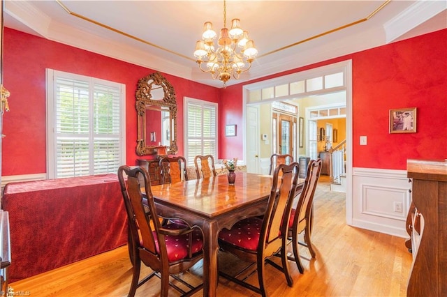 8116 Glengarriff Rd, Clemmons, NC 27012 - dining space with light wood-style floors, a chandelier, a raised ceiling, wainscoting, and ornamental molding