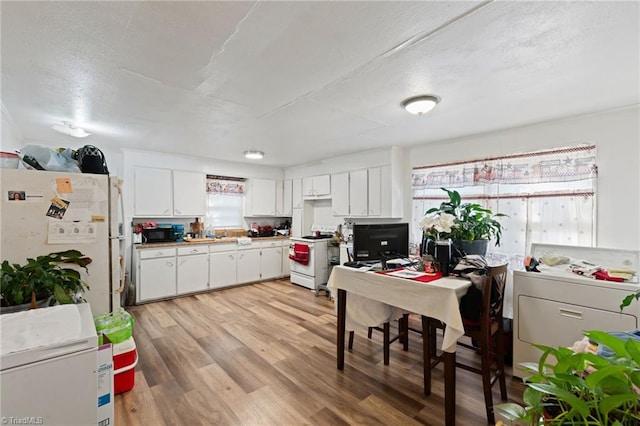 kitchen with white appliances, white cabinetry, and light hardwood / wood-style floors