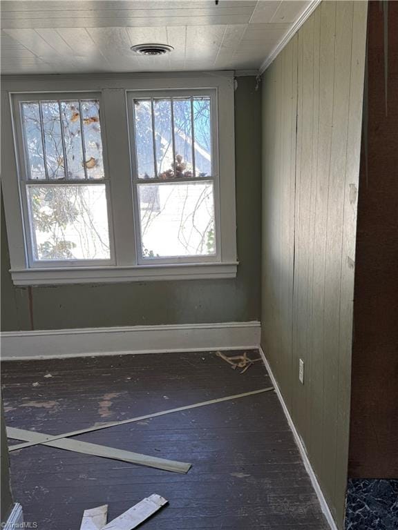 empty room featuring ornamental molding and wood walls