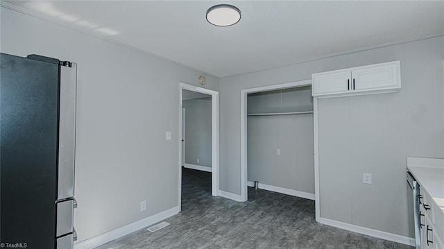 unfurnished bedroom featuring a closet and stainless steel fridge