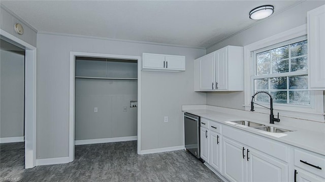 kitchen featuring stainless steel dishwasher, crown molding, white cabinetry, and sink