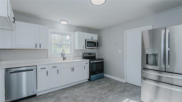 kitchen with crown molding, appliances with stainless steel finishes, sink, and white cabinets