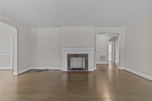 1810 Elm St N, Greensboro, NC 27408 - unfurnished living room featuring wood finished floors, arched walkways, and a brick fireplace