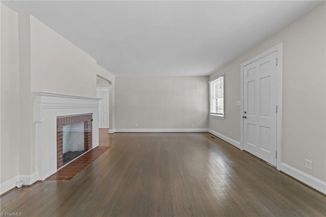 1810 Elm St N, Greensboro, NC 27408 - unfurnished living room with wood finished floors, a brick fireplace, and arched walkways