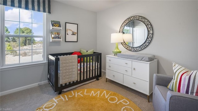 carpeted bedroom featuring multiple windows and a crib