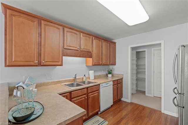 kitchen featuring light countertops, white dishwasher, freestanding refrigerator, and a sink