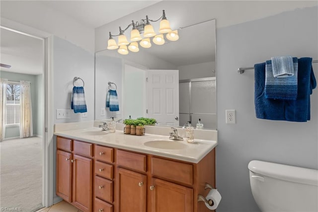 full bath featuring double vanity, an enclosed shower, toilet, and a sink