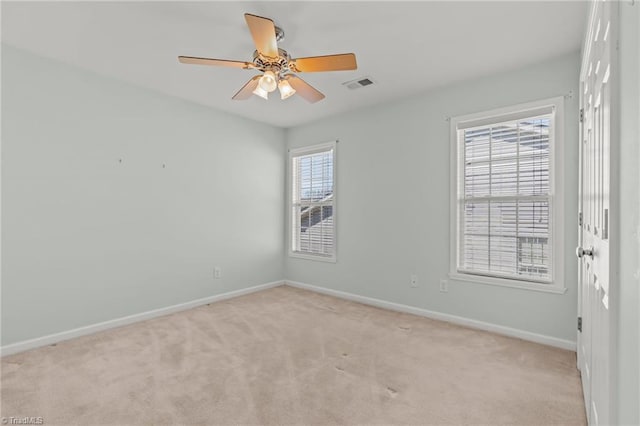 empty room featuring visible vents, light colored carpet, baseboards, and ceiling fan