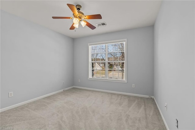 carpeted spare room featuring visible vents, ceiling fan, and baseboards