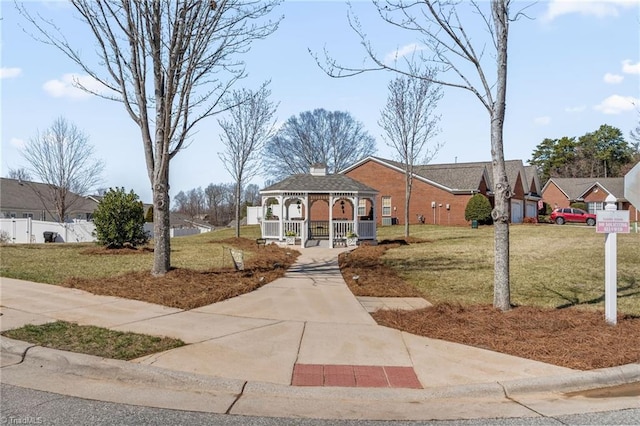 view of front of house with a gazebo, a chimney, a front lawn, and fence