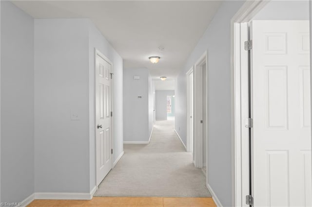 corridor with baseboards and light carpet