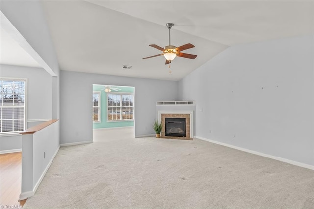 unfurnished living room with a tiled fireplace, visible vents, baseboards, and a wealth of natural light