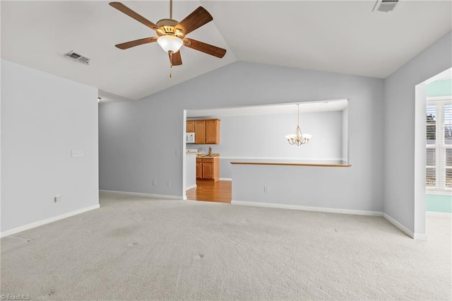 unfurnished living room with visible vents, ceiling fan with notable chandelier, light colored carpet, and vaulted ceiling