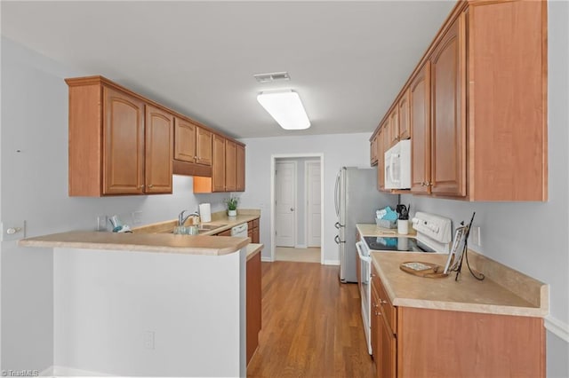 kitchen with white appliances, visible vents, a peninsula, a sink, and light countertops