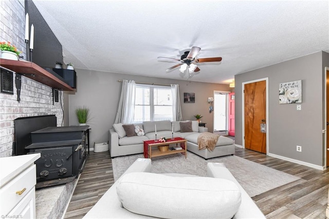 living room featuring a fireplace, dark wood-type flooring, a textured ceiling, and ceiling fan