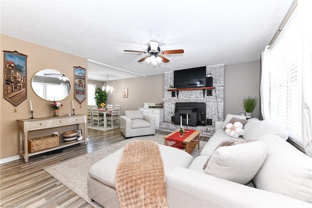 living room featuring ceiling fan, hardwood / wood-style floors, a brick fireplace, and a healthy amount of sunlight