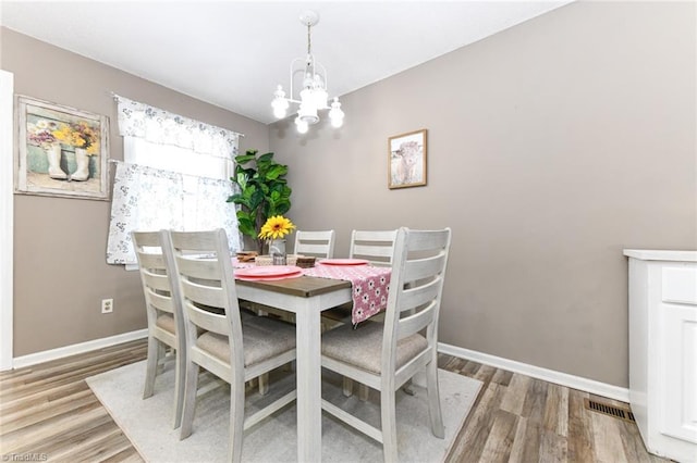 dining space with hardwood / wood-style floors and an inviting chandelier