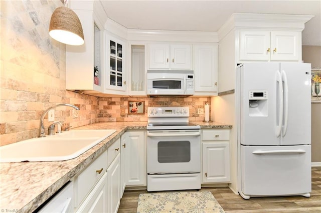 kitchen featuring sink, backsplash, white cabinetry, light wood-type flooring, and white appliances