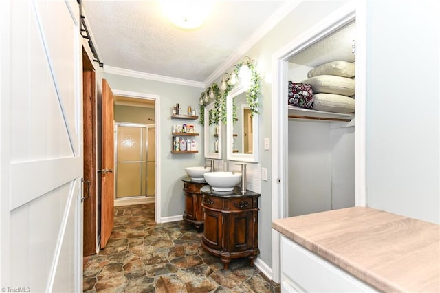 bathroom featuring a textured ceiling, an enclosed shower, vanity, and ornamental molding