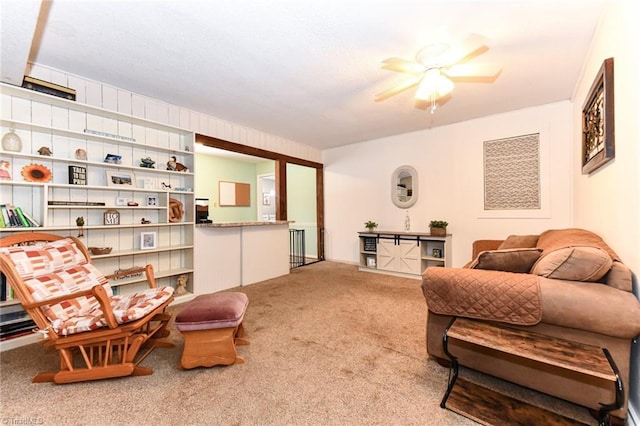 sitting room with ceiling fan and carpet