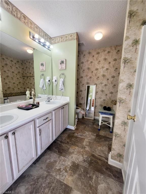 bathroom with toilet, a textured ceiling, and vanity