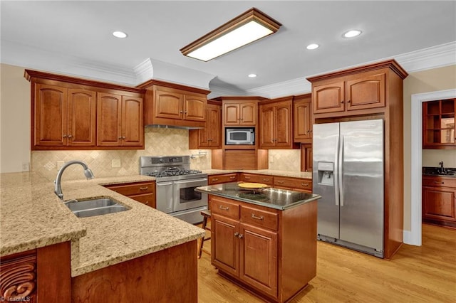 kitchen with a sink, stainless steel appliances, a peninsula, ornamental molding, and light stone countertops
