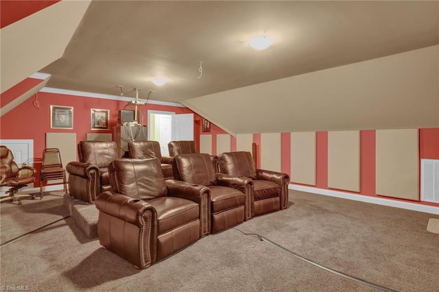 carpeted home theater with ornamental molding and vaulted ceiling