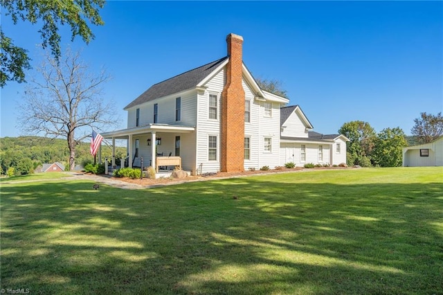 rear view of house with a lawn and covered porch