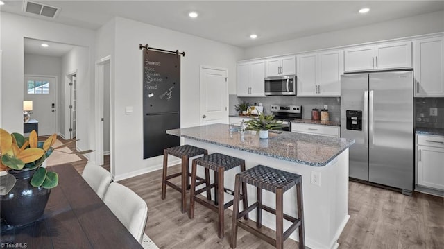 kitchen with white cabinets, dark stone countertops, stainless steel appliances, and a center island