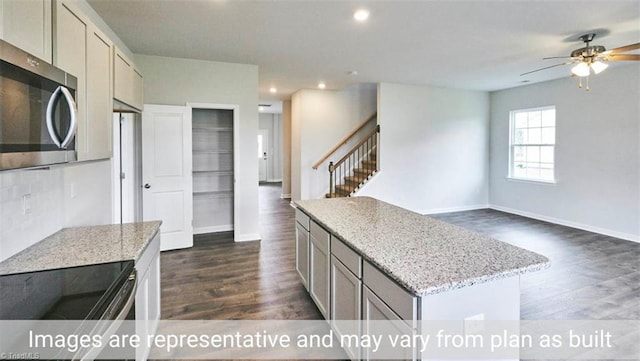 kitchen featuring a center island, gray cabinetry, light stone countertops, and appliances with stainless steel finishes